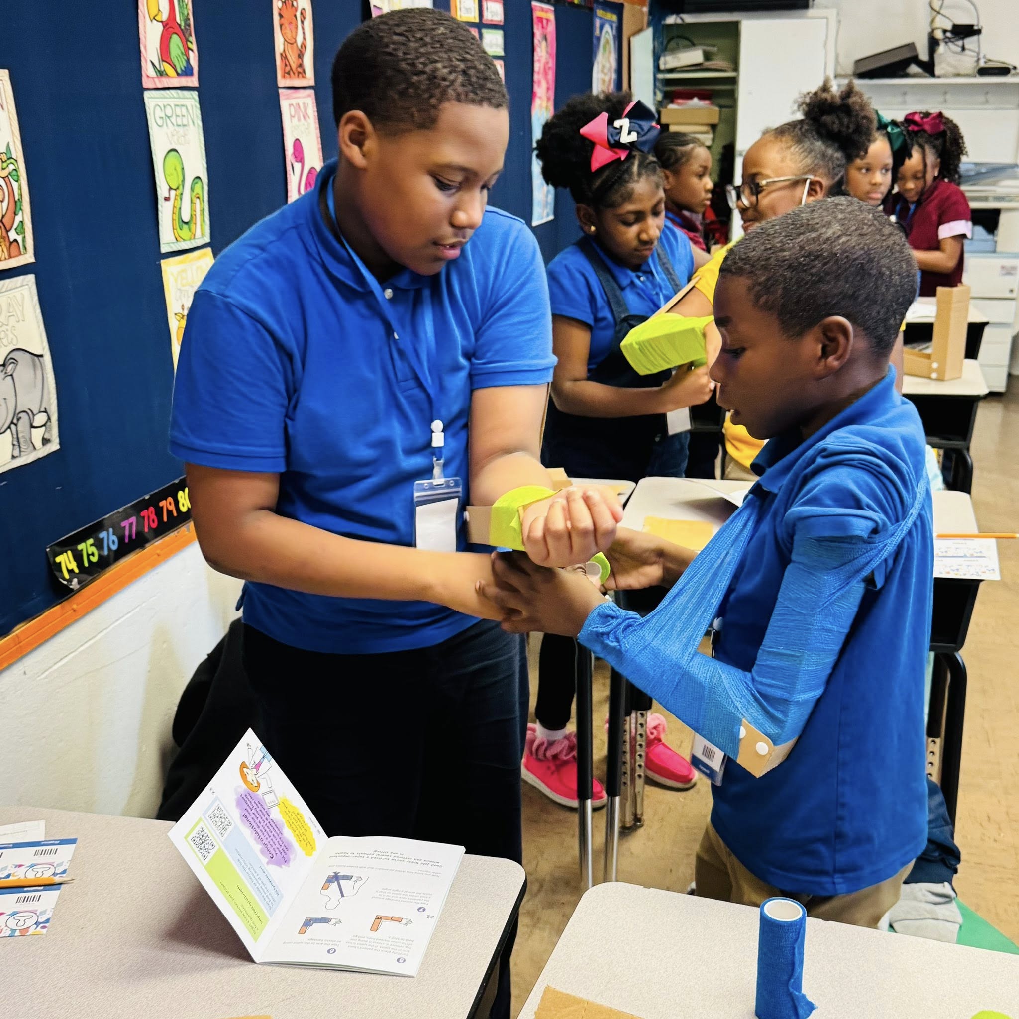 A boy wearing a splint on his arm is helping put a splint on another boy's arm.